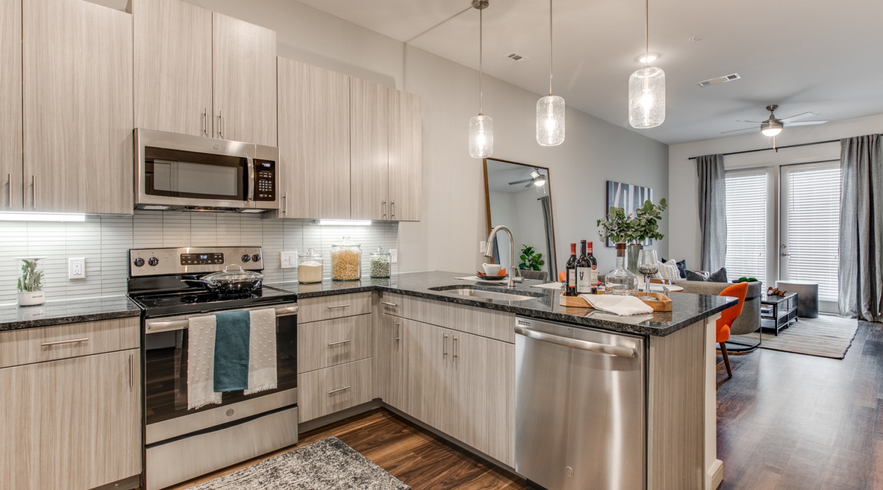 Spacious and well lit kitchen with wood floors and stainless steel appliances 