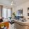 Spacious and well lit living room with wood flooring, large windows and open access to the kitchen