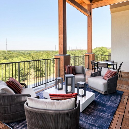The outdoor lounge at our apartments for rent in Grapevine, TX, featuring cushioned chairs and wood grain flooring.