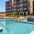 The pool area at our apartments in Grapevine, TX, featuring beach chairs, umbrellas, and a view of the apartment complex.